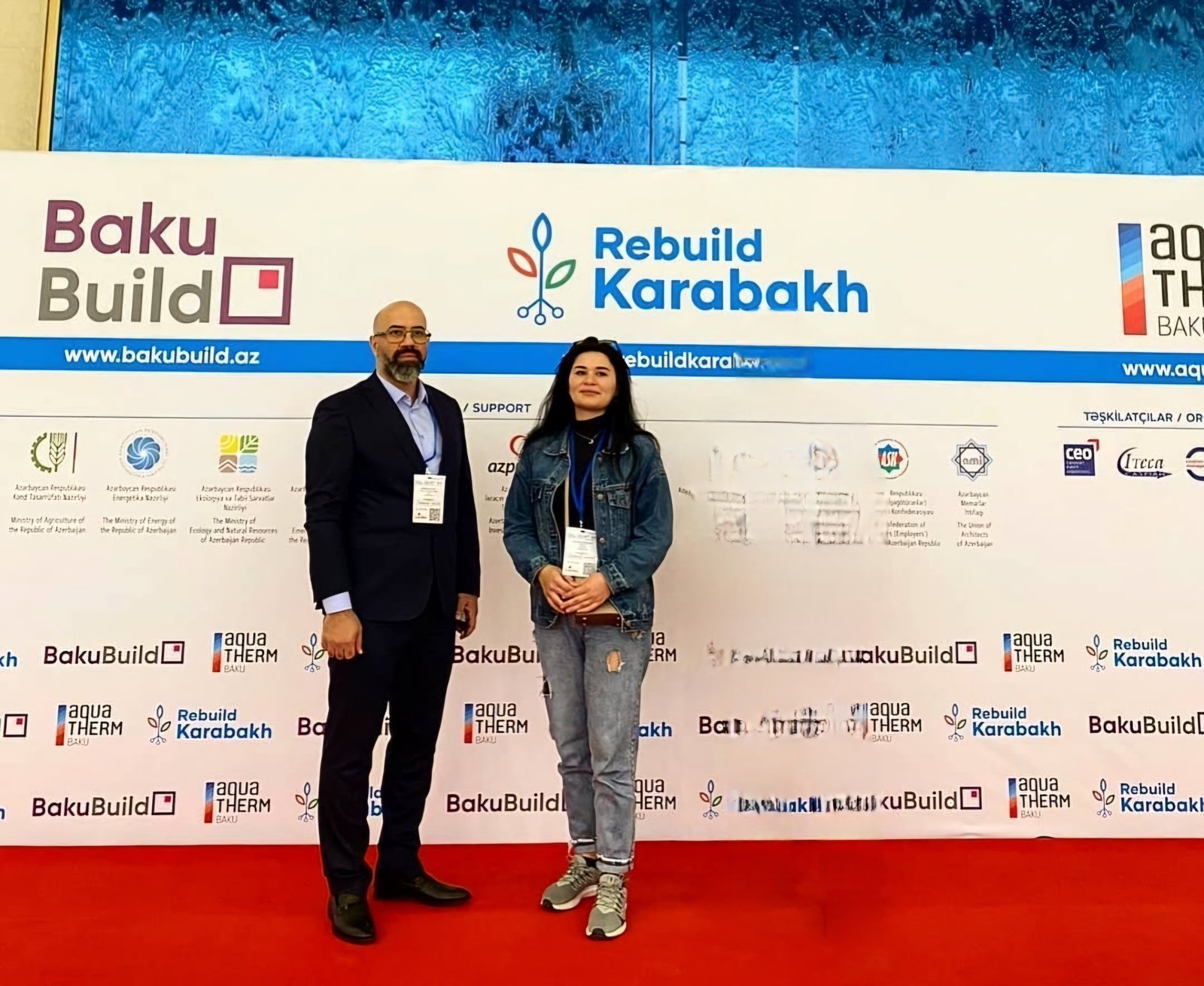 "Rebuild Karabakh" və BakuBuild sərgisinin lövhəsi önündə çəkilmiş foto, 28 noyabr 2023